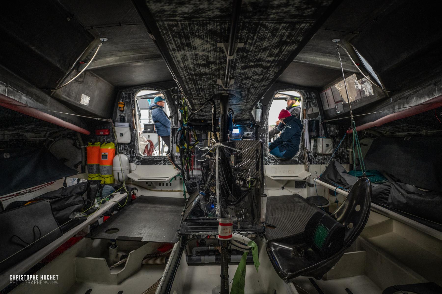 Intérieur technique du voilier IMOCA Lazare avec cockpit en carbone et marins aux écoutilles à Saint-Malo.