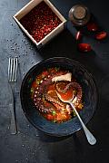 Poulpe braisé dans un bouillon de tomates cerises avec poivre rose et herbes fraîches en clair-obscur