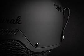 Détail d’un casque de ski noir mat Aurak avec éclairage studio rasant mettant en valeur les textures et le logo.