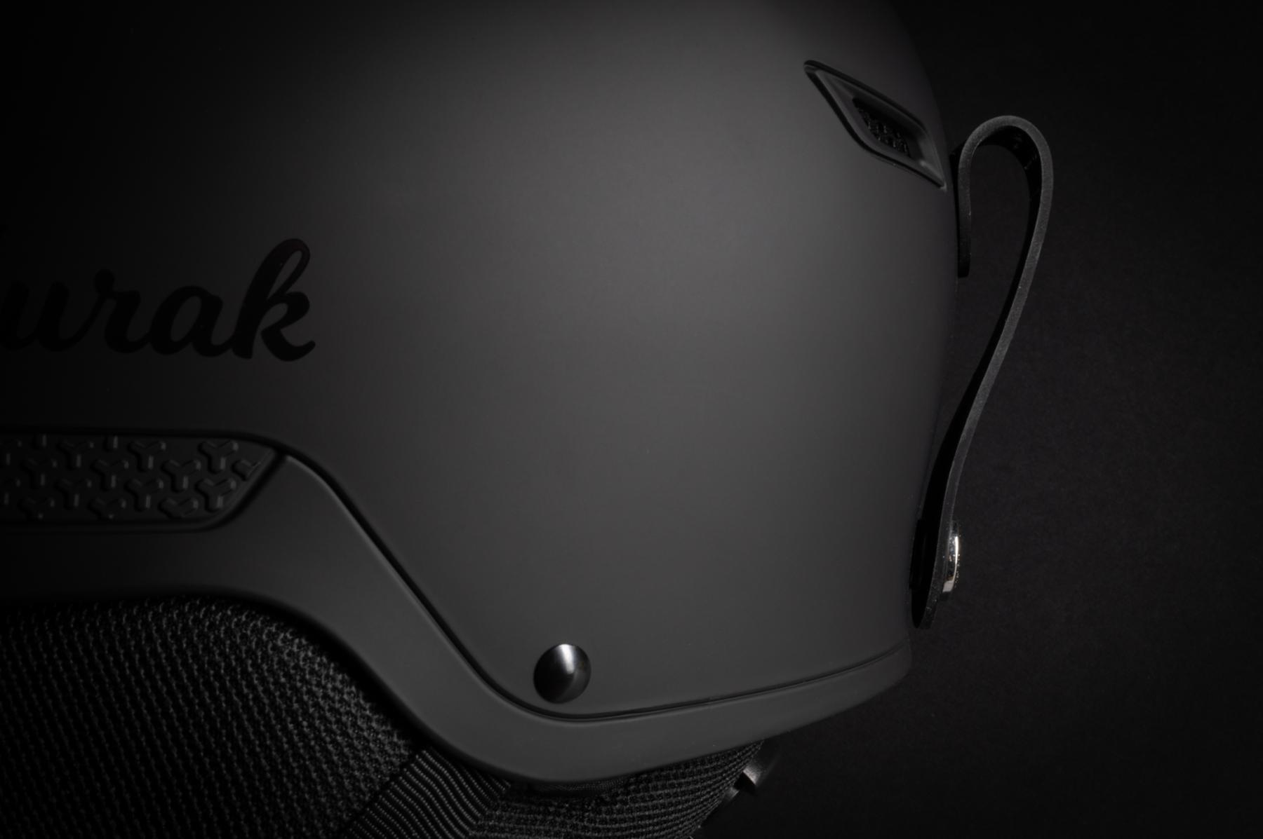 Détail d’un casque de ski noir mat Aurak avec éclairage studio rasant mettant en valeur les textures et le logo.