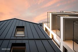 Façade en métal sombre et balcons blancs ajourés du Millésime à Rennes sous un ciel orangé de fin de journée.