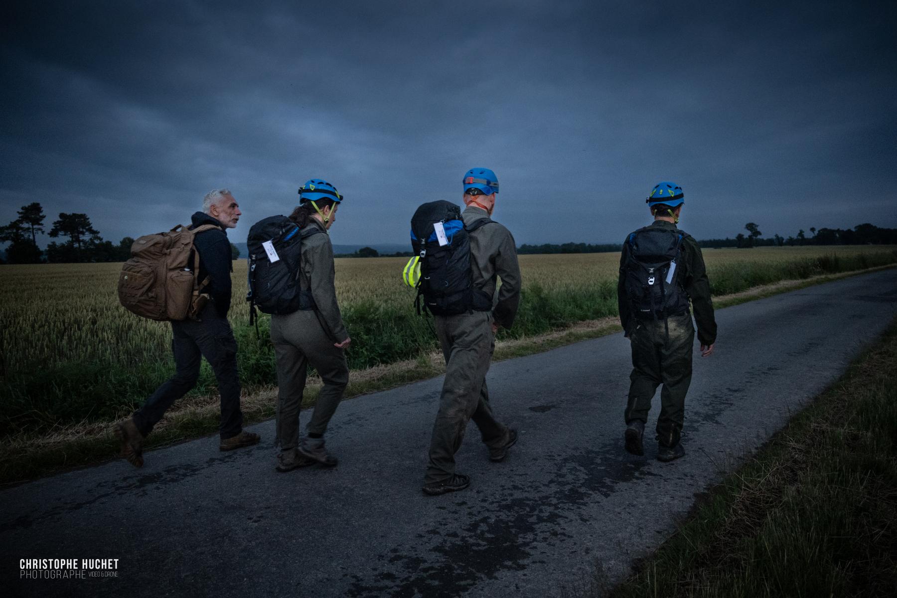 Quatre participants casqués marchent sur une route à l’aube lors d’un raid de formation au leadership 
