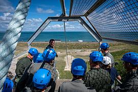 Groupe casqué sur plateforme métallique dominant la mer lors d’un exercice de leadership en Bretagne.