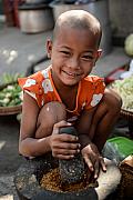 Photo Petite fille préparant des épices avec un mortier et un pilon traditionnel dans la région de Mandalay (Birmanie)