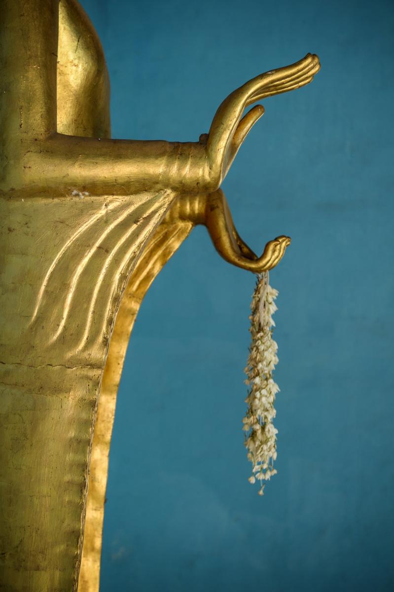 Photo Détail d’une statue de Bouddha dorée à Bagan, tenant une guirlande de fleurs en offrande