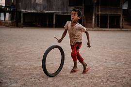 Photo Jeune garçon faisant rouler un pneu à l’aide d’un bâton, un jeu traditionnel dans un village près du lac Inle en Birmanie