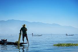 Photo Un pêcheur traditionnel Intha sur son embarcation et le lac Inle en Birmanie (Myanmar), utilisant la technique de rame avec la jambe 