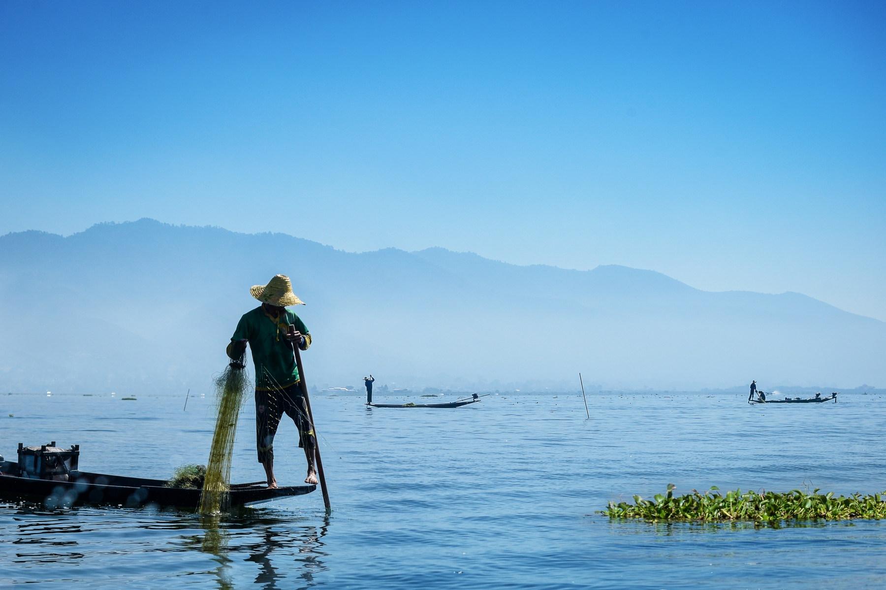 Photo Un pêcheur traditionnel Intha sur son embarcation et le lac Inle en Birmanie (Myanmar), utilisant la technique de rame avec la jambe 