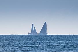Deux trimarans Ultim (Actual et Sodebo) naviguant sur la ligne d’horizon par temps clair au large de Lorient lors d’une course.