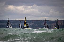 Voiliers IMOCA dont Café Joyeux sur mer agitée devant les falaises du Havre par temps couvert.