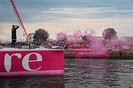 Coque rose,l’ IMOCA Lazare et skipper Tanguy Le Turquais dans une fumée rose lors du départ aux Sables d’Olonne.