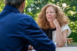 Femme rousse en discussion lors d’une formation en plein air, lumière du jour sur fond de parc verdoyant.