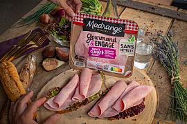 Tranches de jambon sur tartines avec figues et herbes sur table en bois rustique sous lumière naturelle.