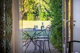 Mobilier en fer forgé sur une terrasse ensoleillée ouvrant sur un parc arboré au Château de Keravéon.