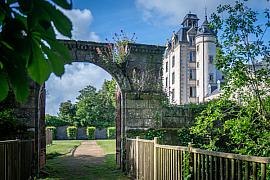 Arche de pierre fleurie ouvrant sur la tour du château de Kéravéon à Erdeven sous un ciel bleu.