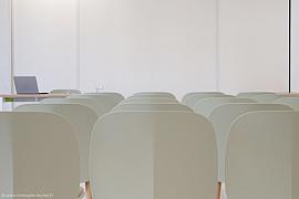 Chaises beiges alignées et ordinateur portable dans une salle de réunion lumineuse au Campus Frassati de Rennes