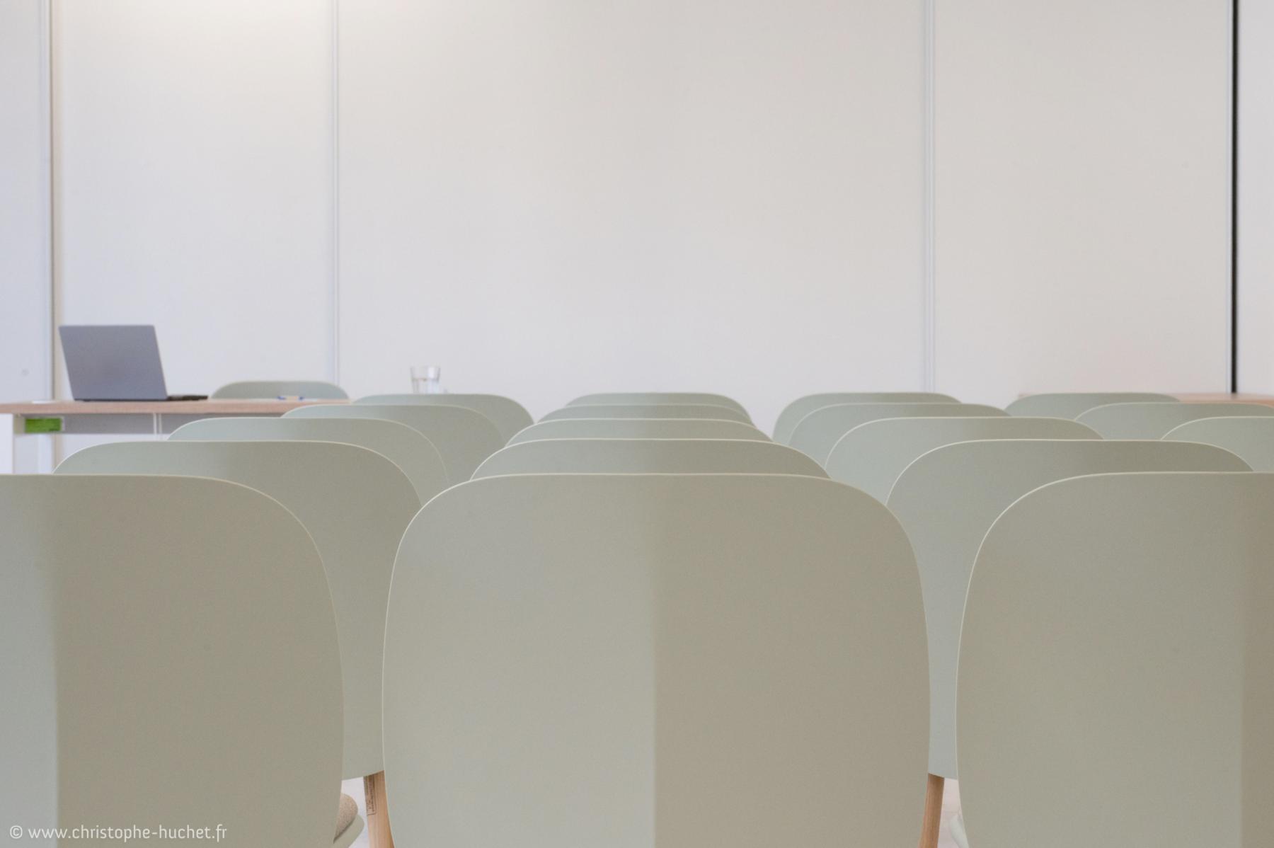 Chaises beiges alignées et ordinateur portable dans une salle de réunion lumineuse au Campus Frassati de Rennes